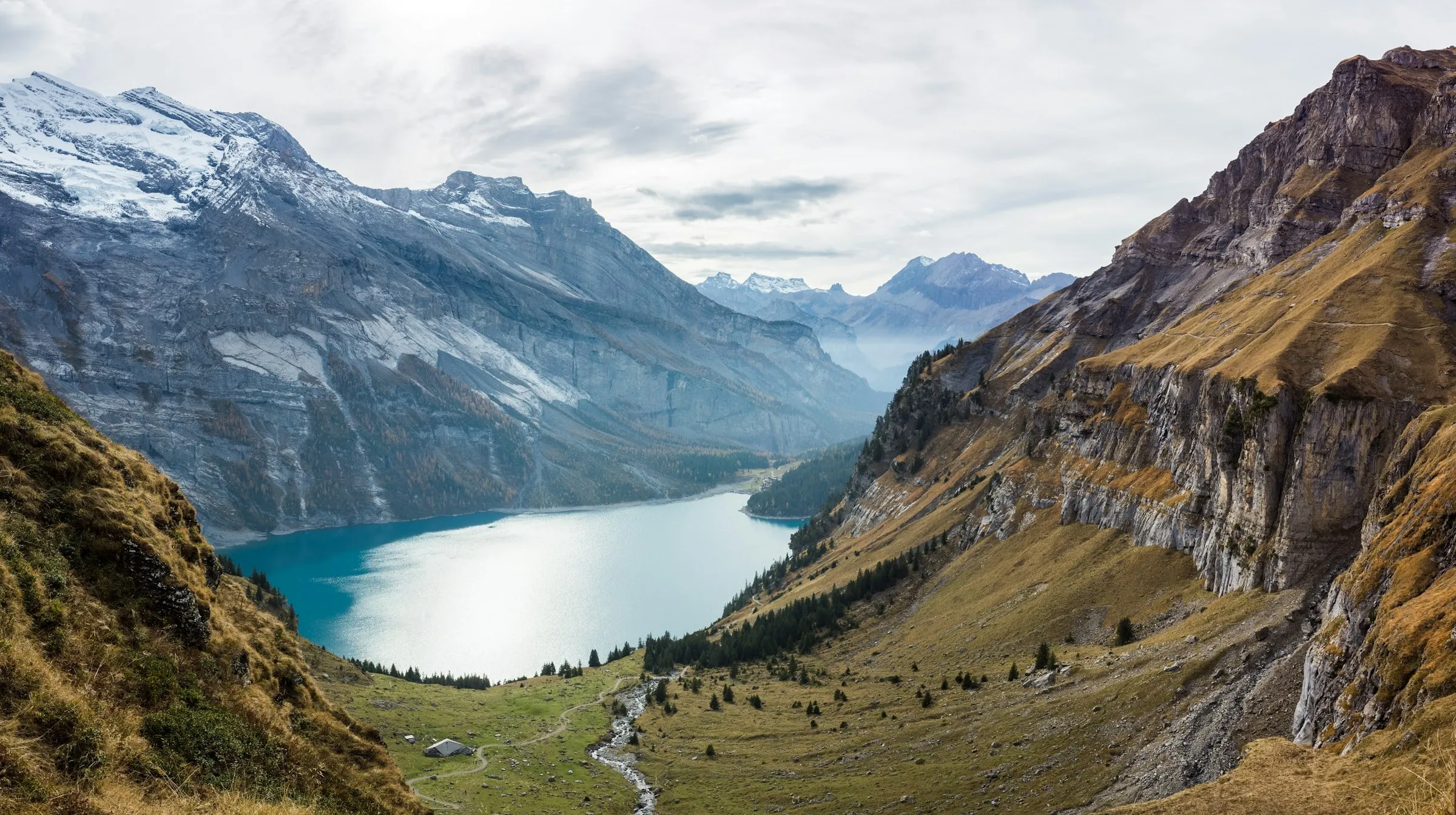 Blick von oben auf den türkisfarbenen Oeschinensee zwischen hohen Felswänden